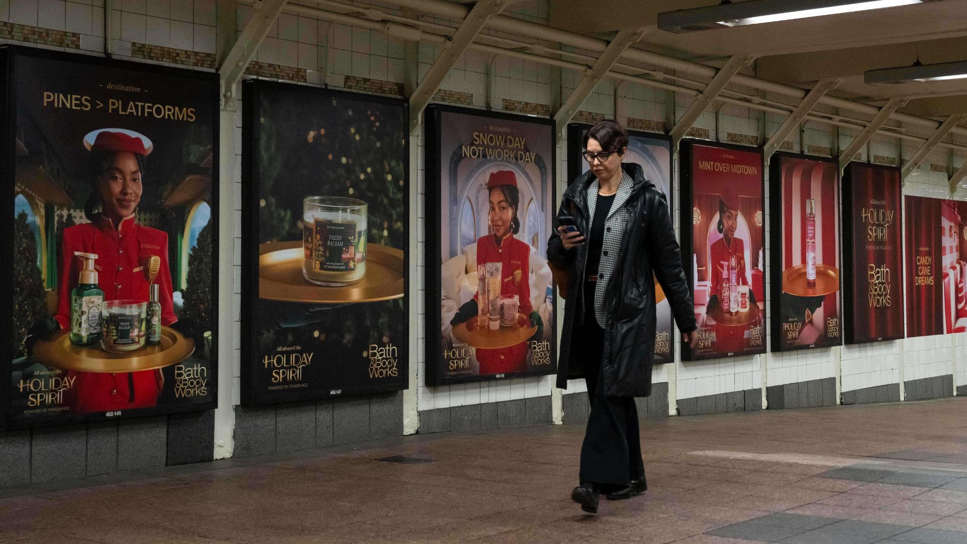 Woman walking in grand central station where bath and body works products are sprayed and ads are on display