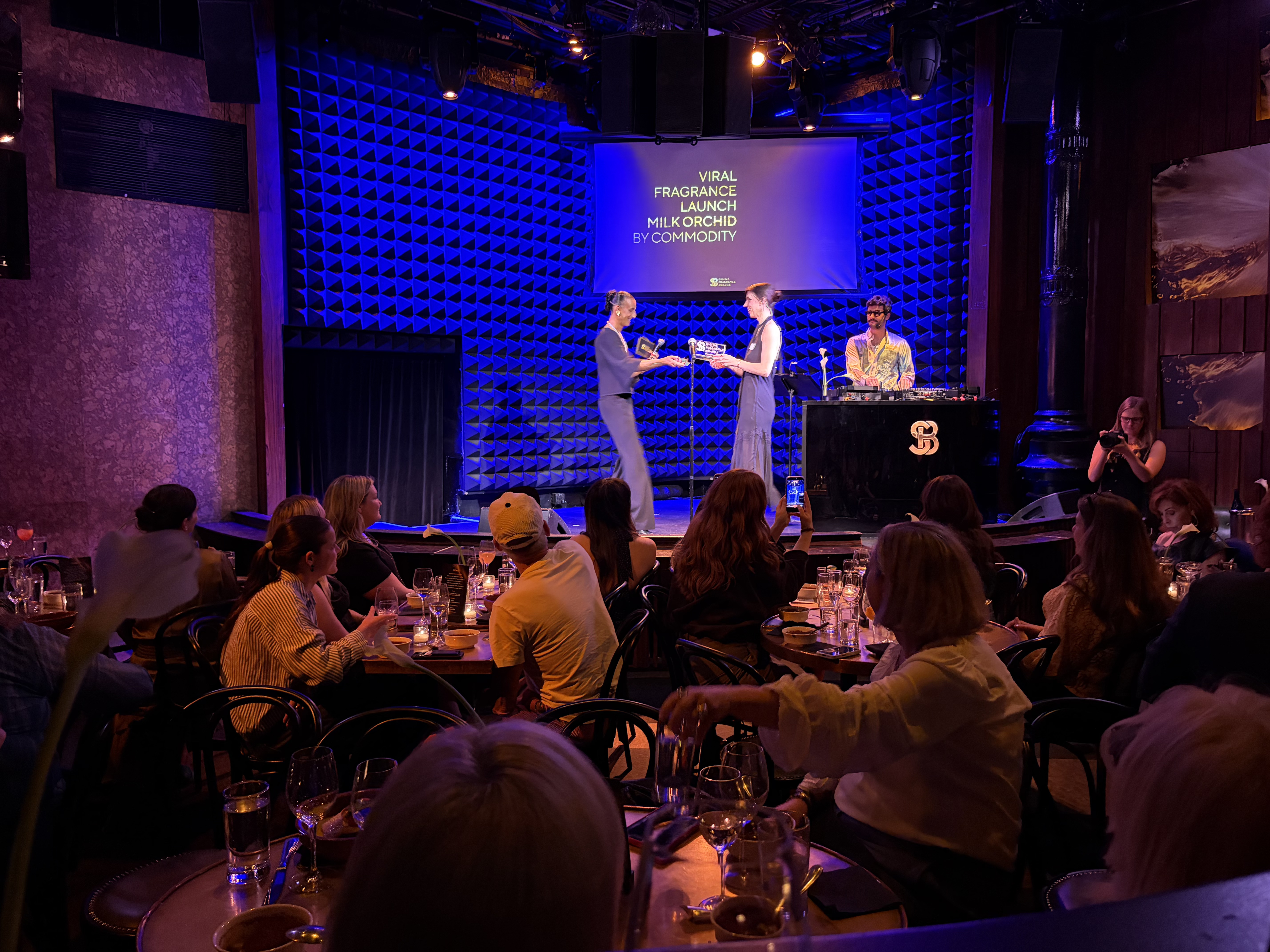 Live awards ceremony with presenters on stage announcing Milk Orchid by Commodity as Viral Fragrance Launch winner at the Scentbird Digital Fragrance Awards.